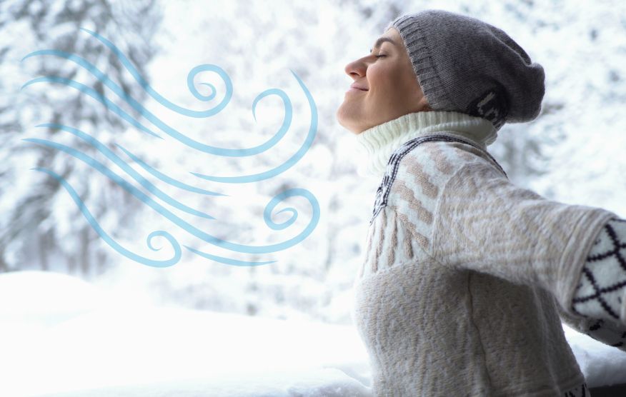 Frau atmet in winterlicher Landschaft tief ein